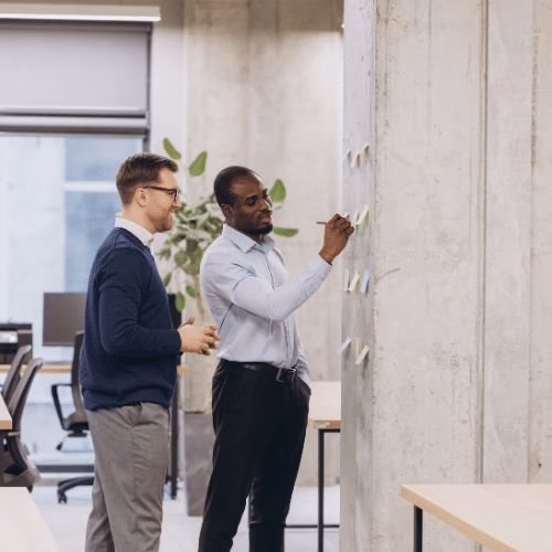Content Marketing Strategie strukturiert entwickeln – HAI Strategies Zwei Content-Marketing-Spezialisten planen eine Content Marketing Strategie mit Notizen an der Wand – HAI Strategies (Symbolbild)