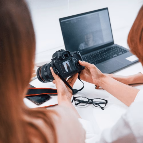Content-Produktion als Teil der Social Media Strategie Zwei Kreative überprüfen Social Media Content auf der Kamera im Rahmen einer Social Media Strategie – HAI Strategies